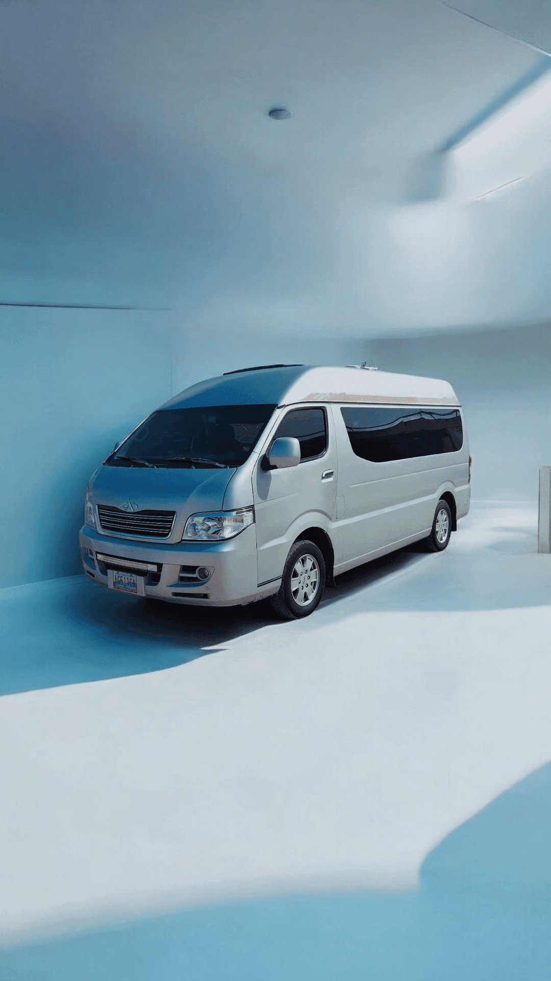 White passenger van parked in a minimalistic blue and white room with natural light.