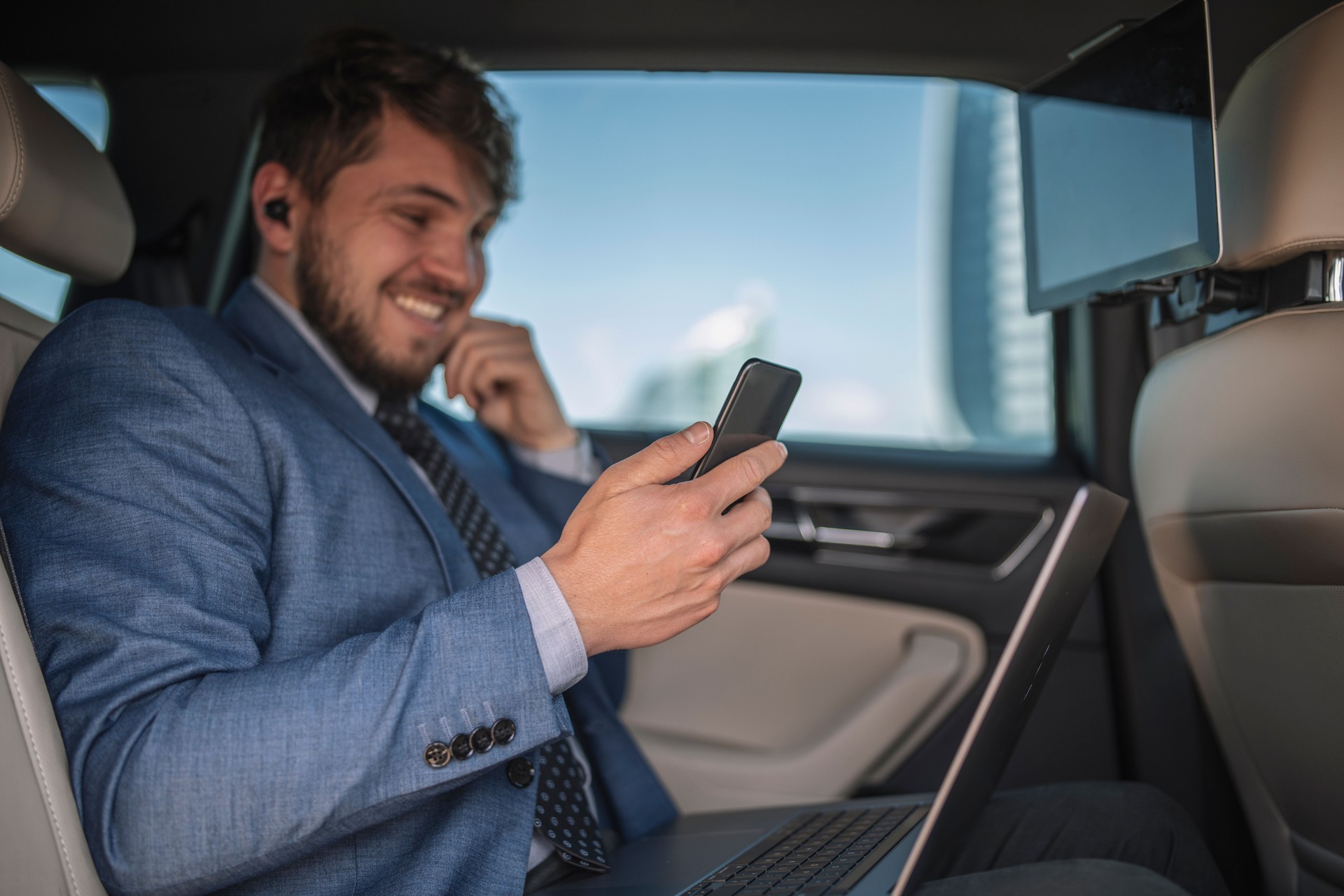 Young entrepreneur smiling while looking at his phone during business trip.